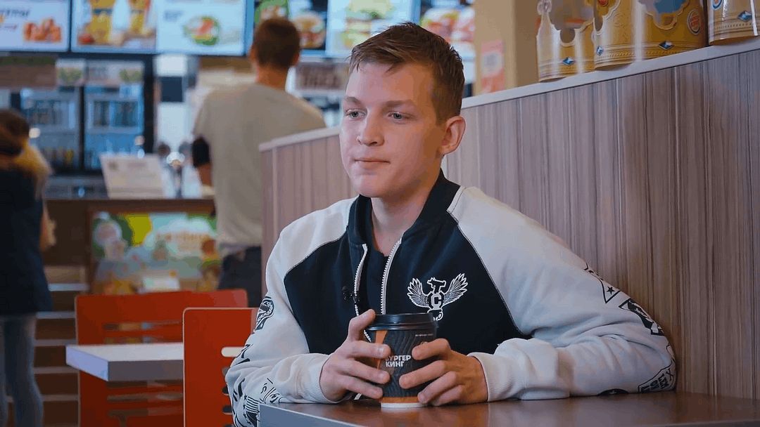 Кадр из рекламы «Бургер Кинг»: Иван со стаканом кофе за столиком